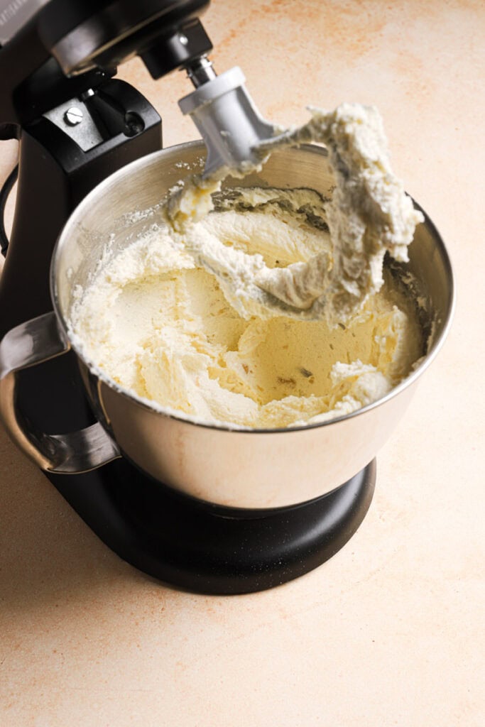 A stand mixer with a bowl filled with creamed butter and sugar.