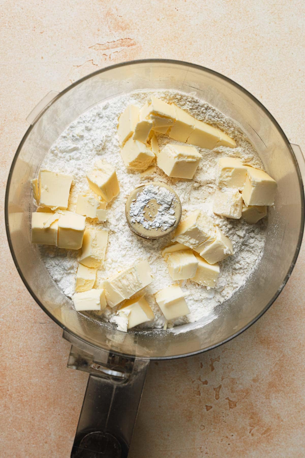 A food processor with flour and pieces of butter.
