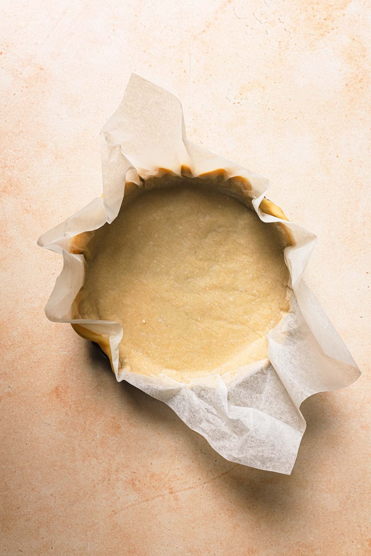 Shortcrust dough topped with parchment paper over a tart pan.