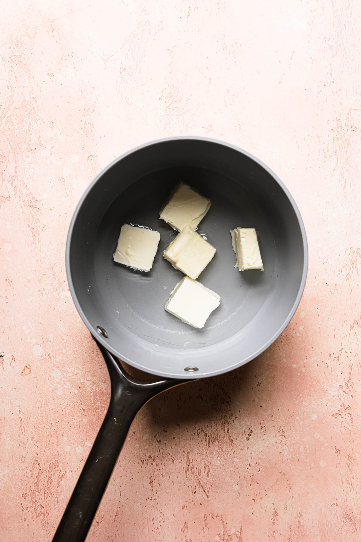 Water and pieces of butter in a sauce pan.