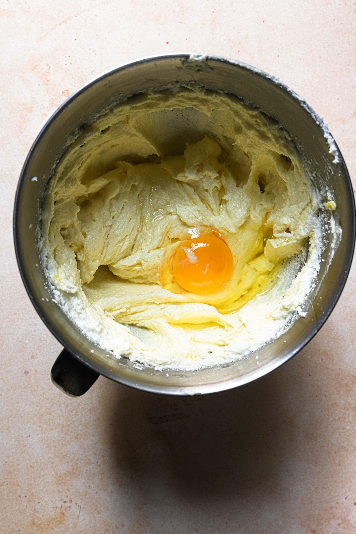 A mixer bowl with creamed butter and sugar and an egg.
