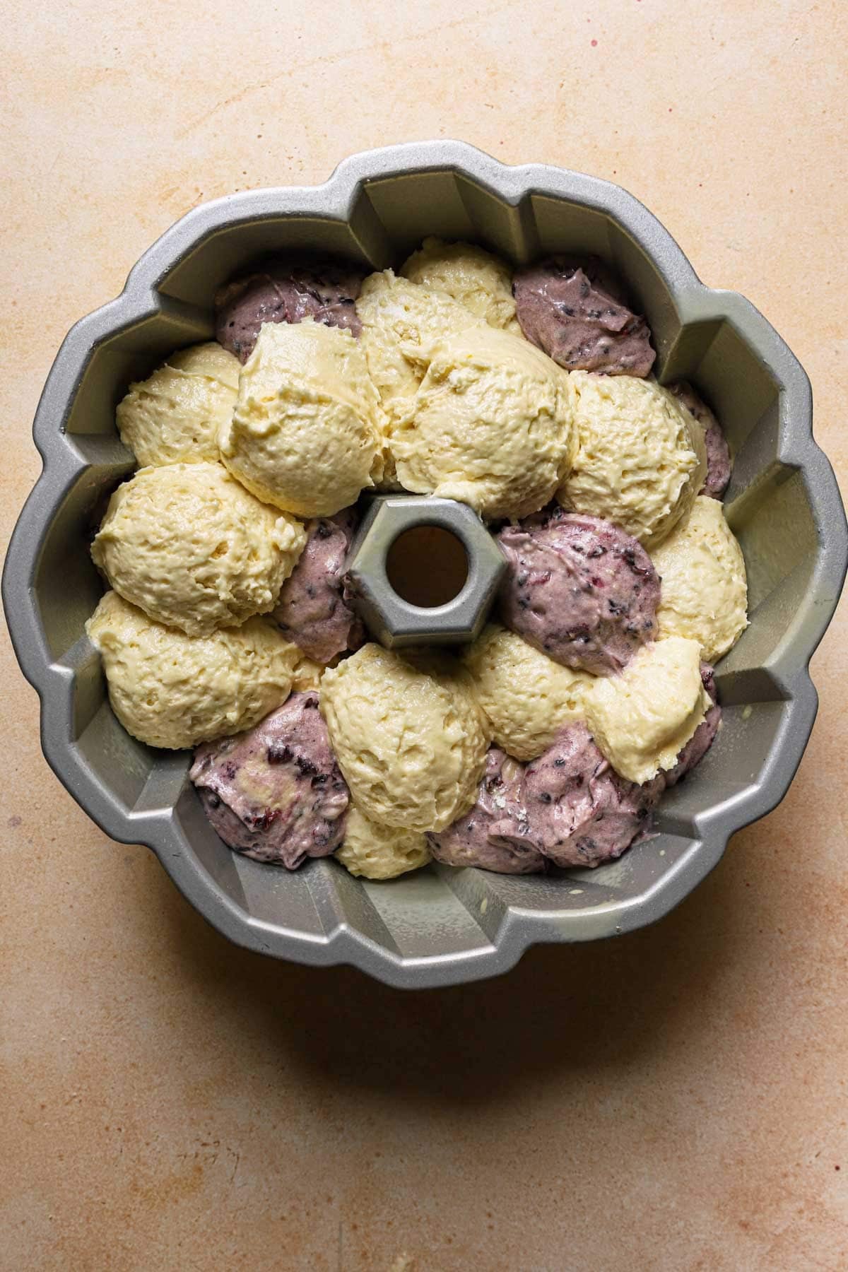 A bundt pan filled with lemon batter and blackberry batter.