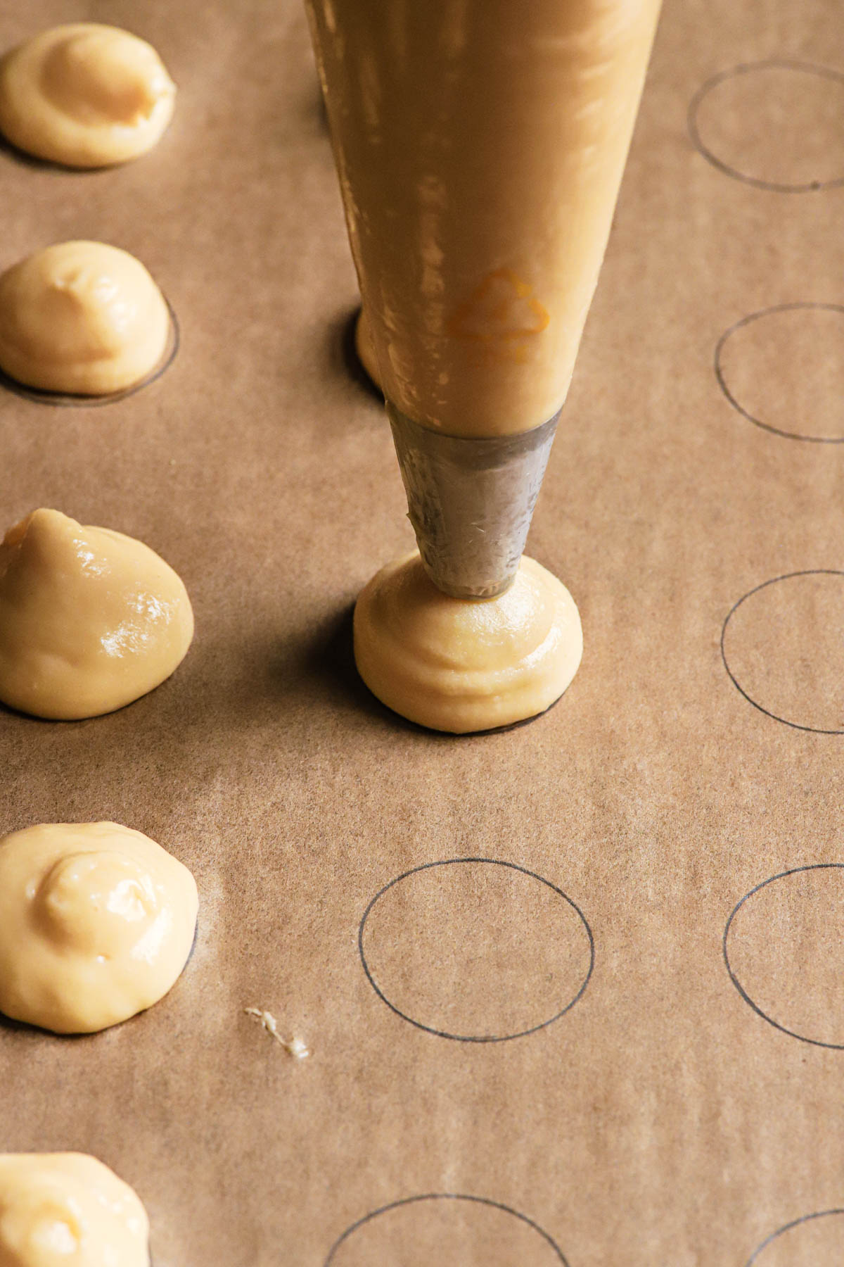 Piping cream puff dough over a large baking sheet.