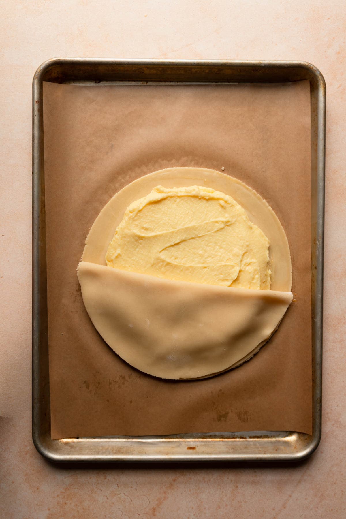 A cookie sheet topped with pastry cream and another layer of dough.