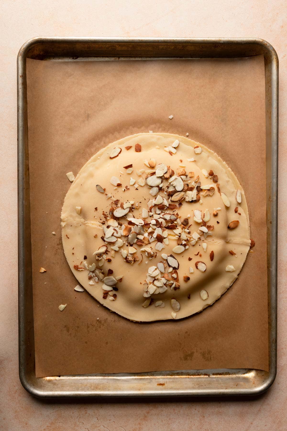 Free form italian tart, unbaked sprinkled with almonds.