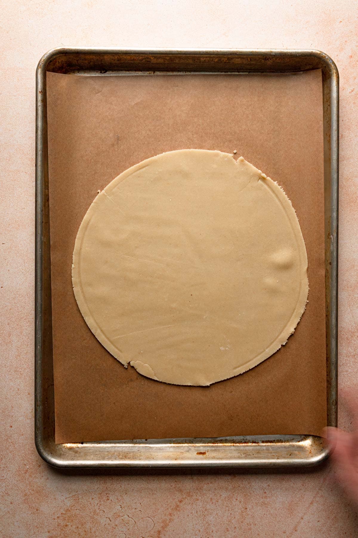 A cookie sheet topped with a circle dough.