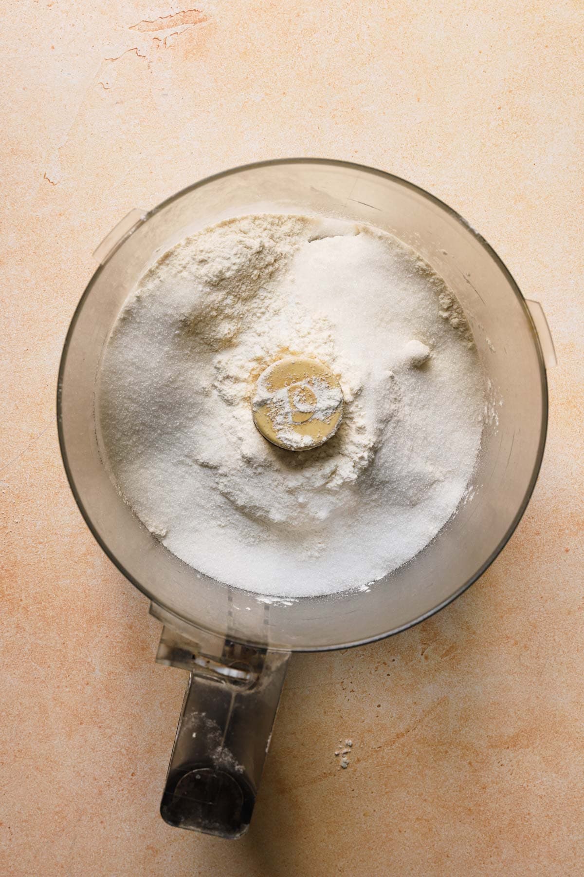 A food processor bowl with flour and sugar.