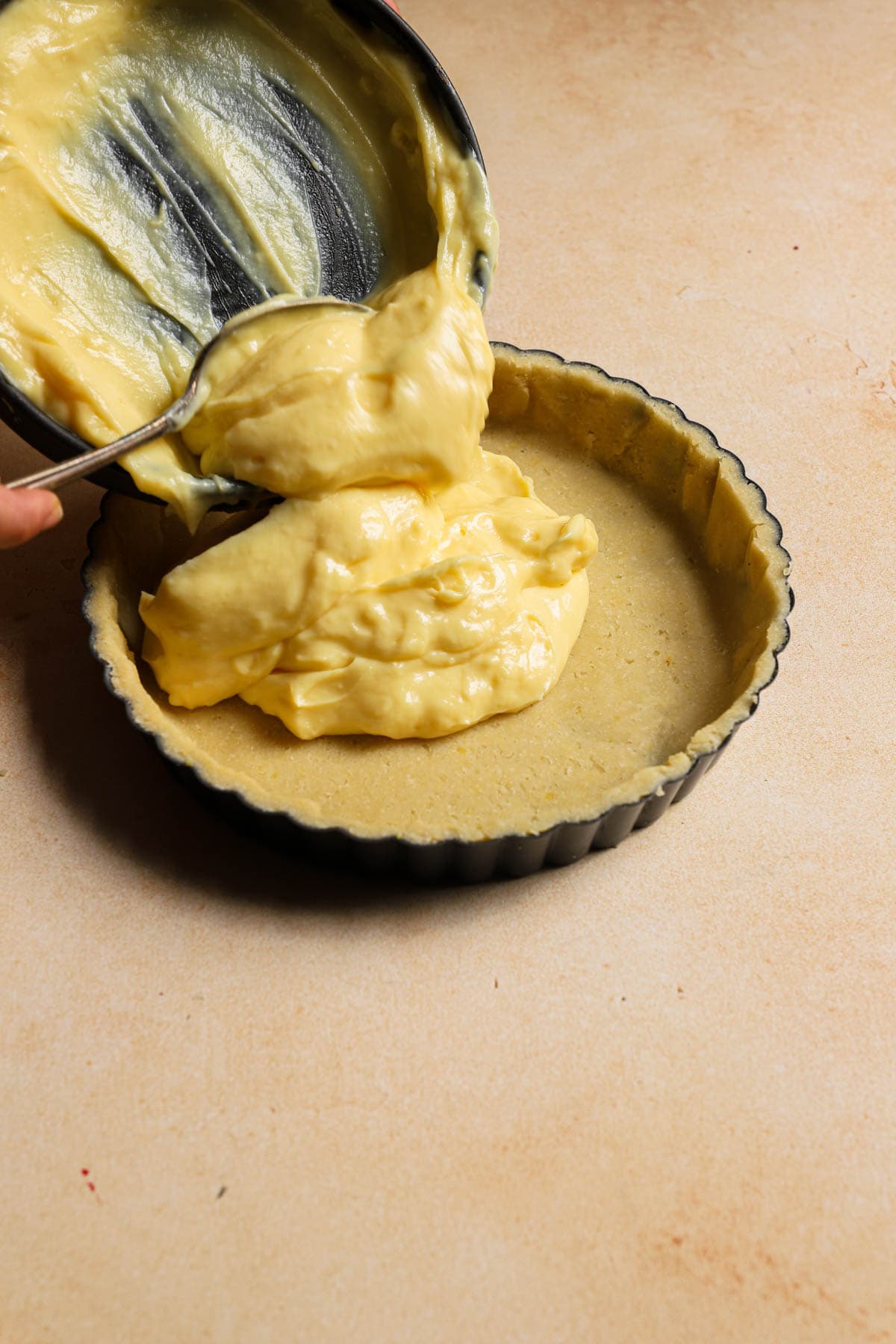 Filling a tart pan lined with dough with italian pastry cream.