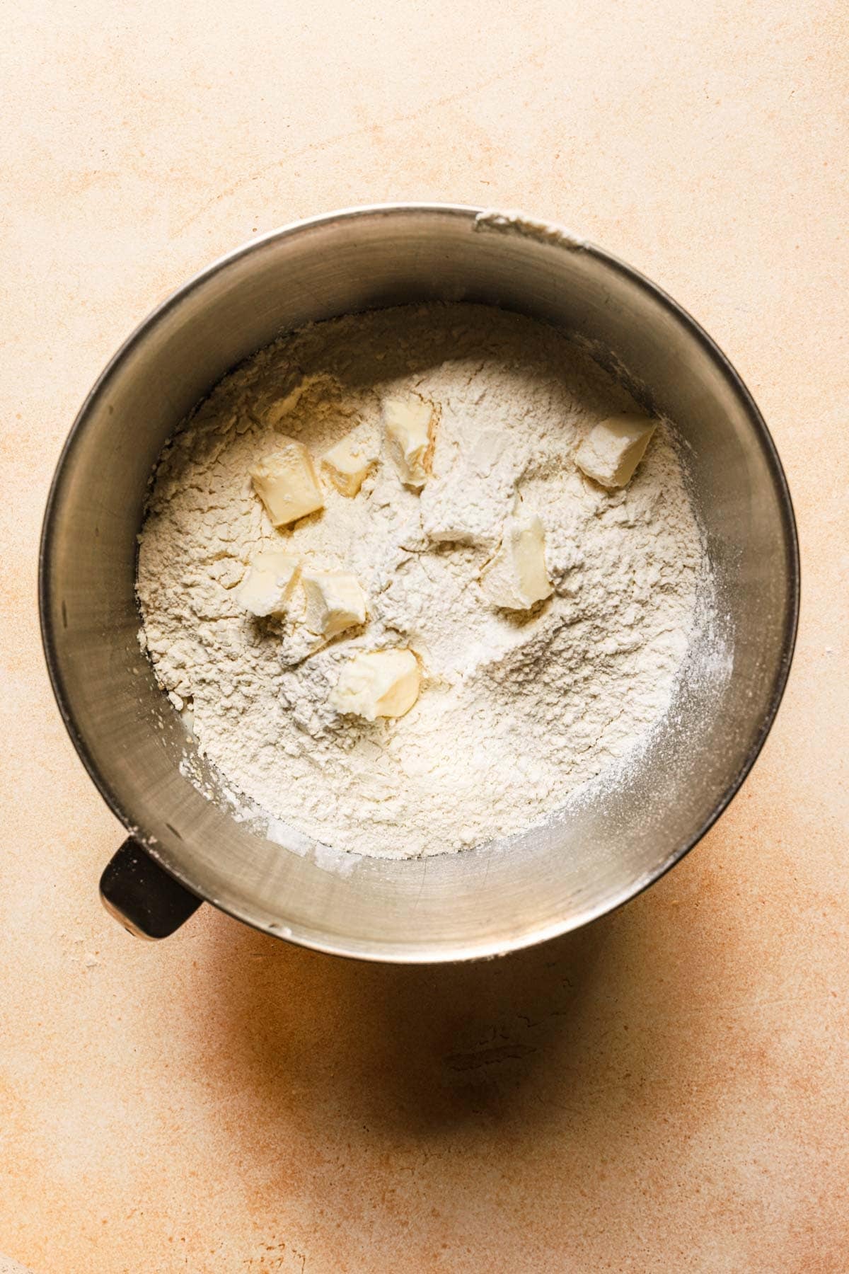 A mixing bow with flour and pieces of butter.