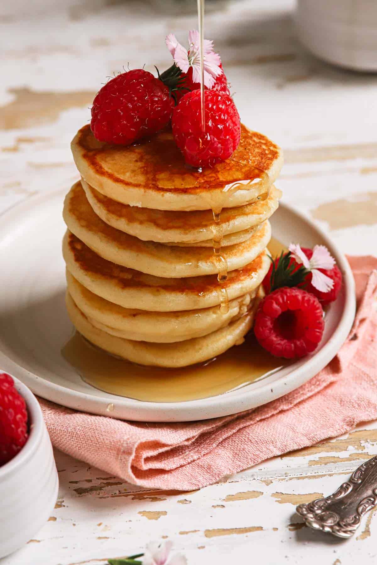 a stack of mini pancakes with raspberries