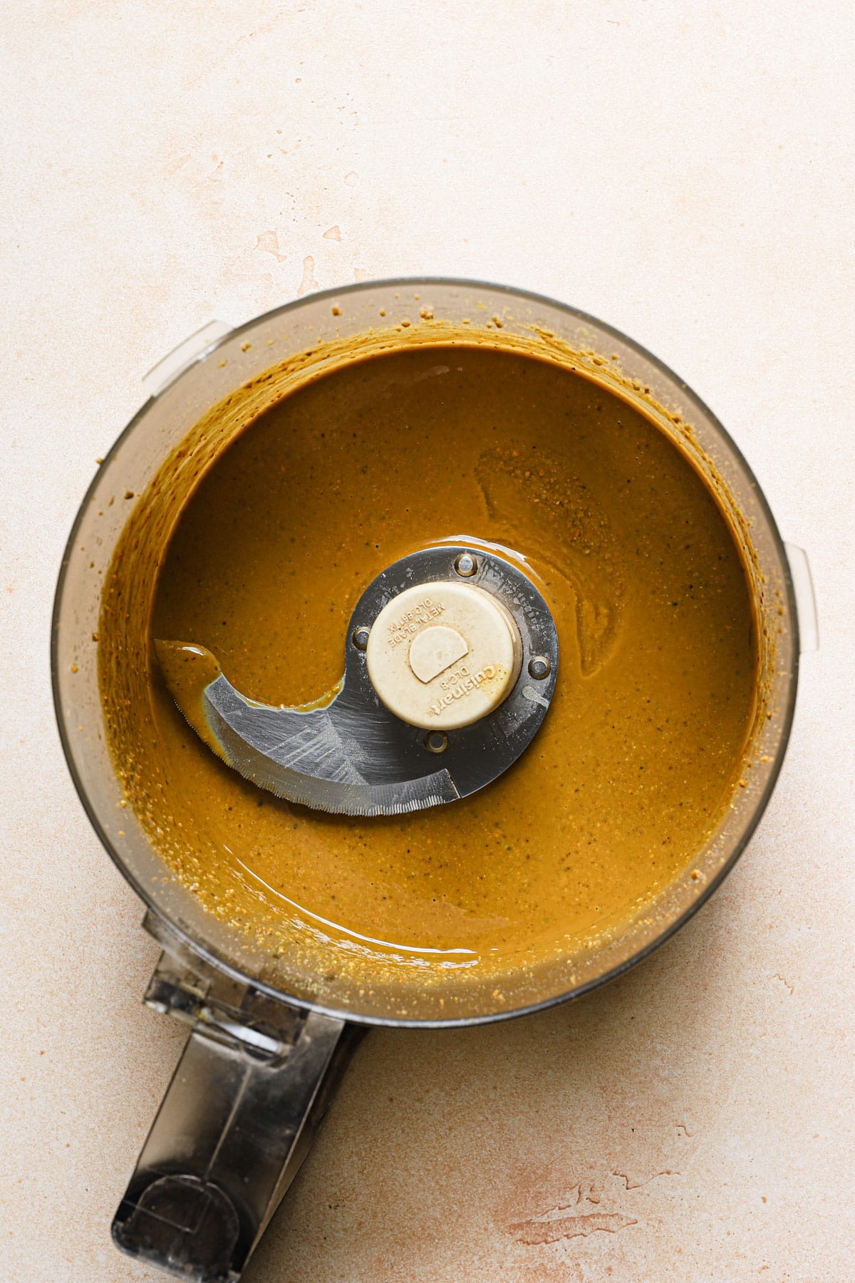 A food processor bowl with oily pistachio mixture.