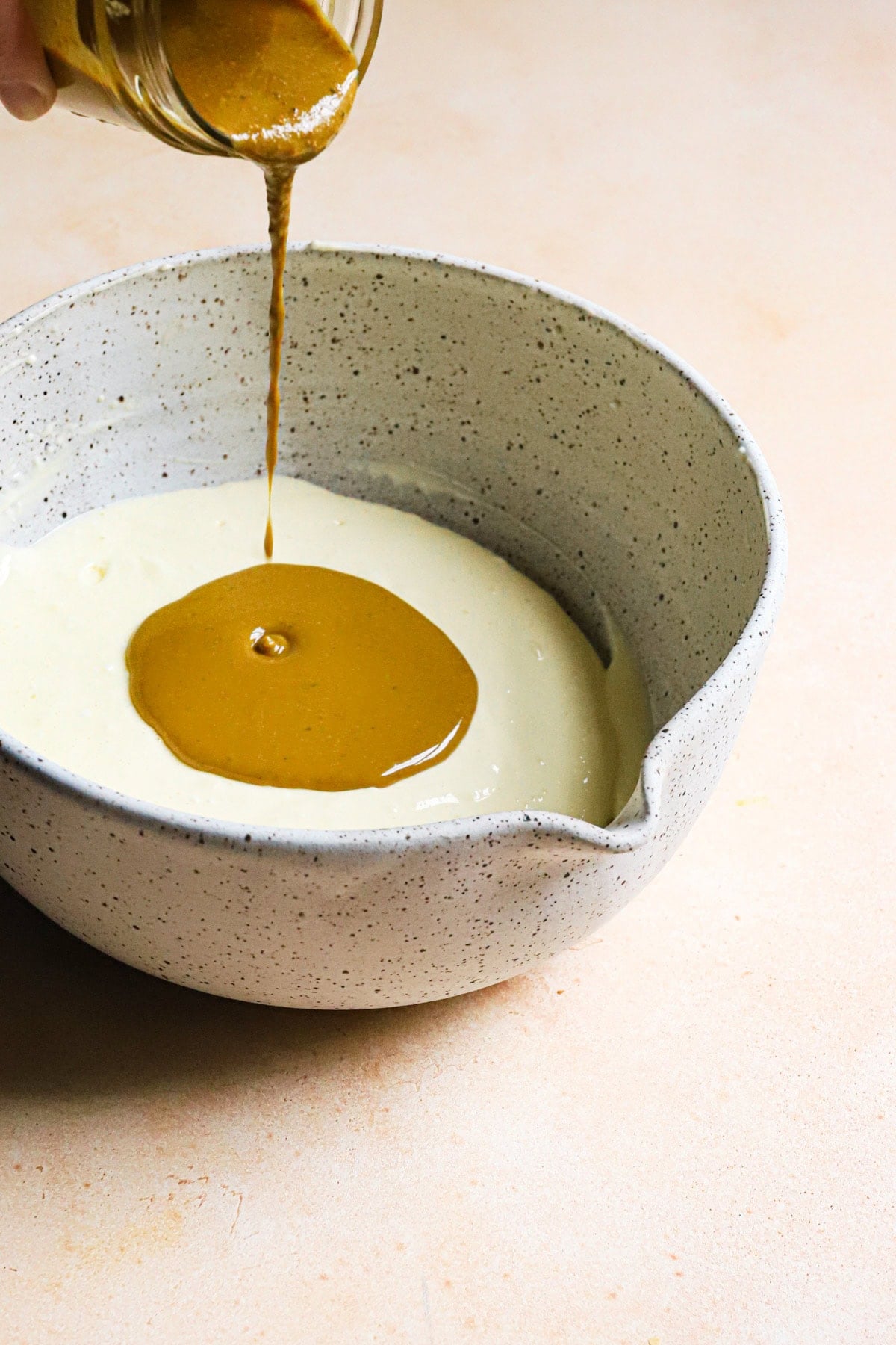 Pouring pistachio paste into cream cheese mixture.