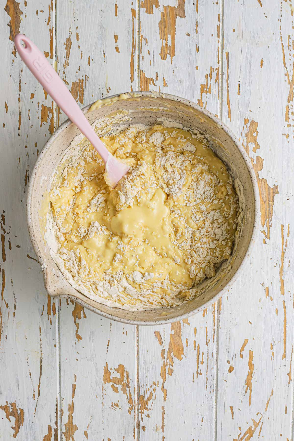 A large bowl with a spatula and muffins batter.