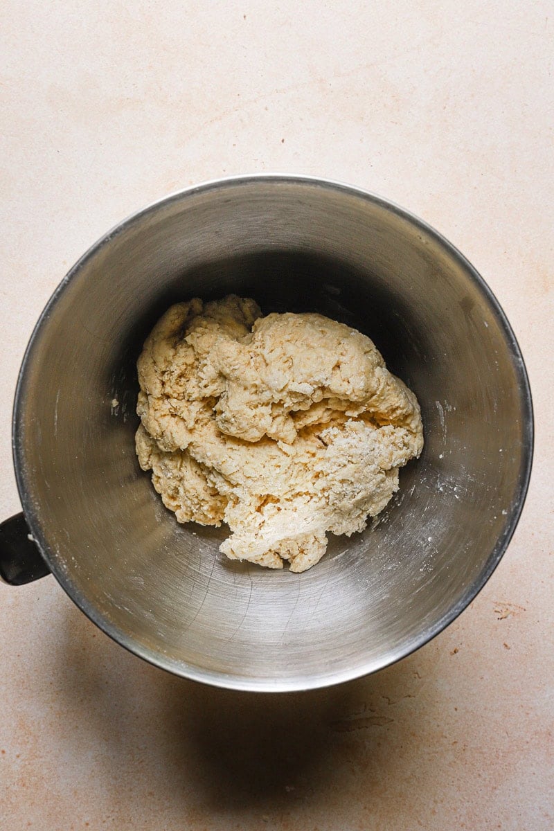 Shaggy, dense dough in a bowl of a stand mixer.