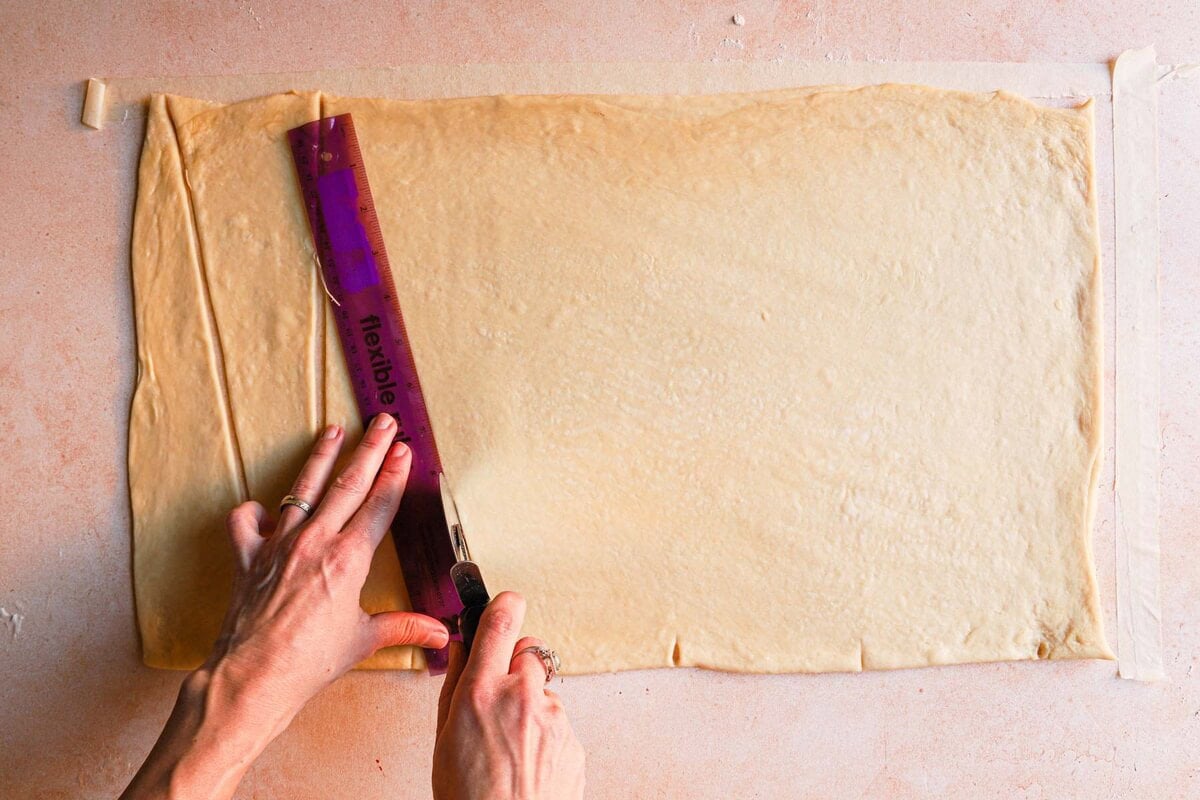 Using a ruller to cut rectangle dough into triangles.