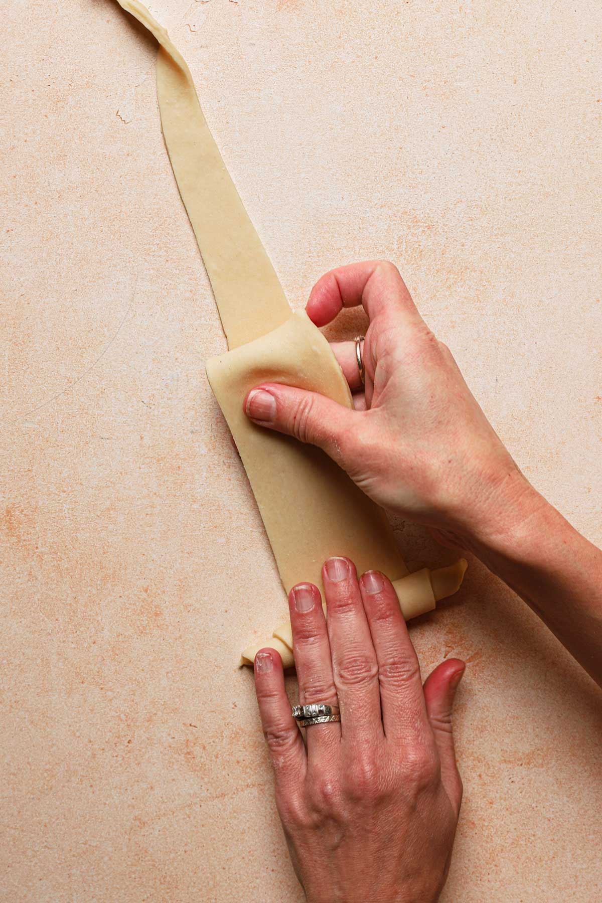 hands rolling crescent shape pastry.
