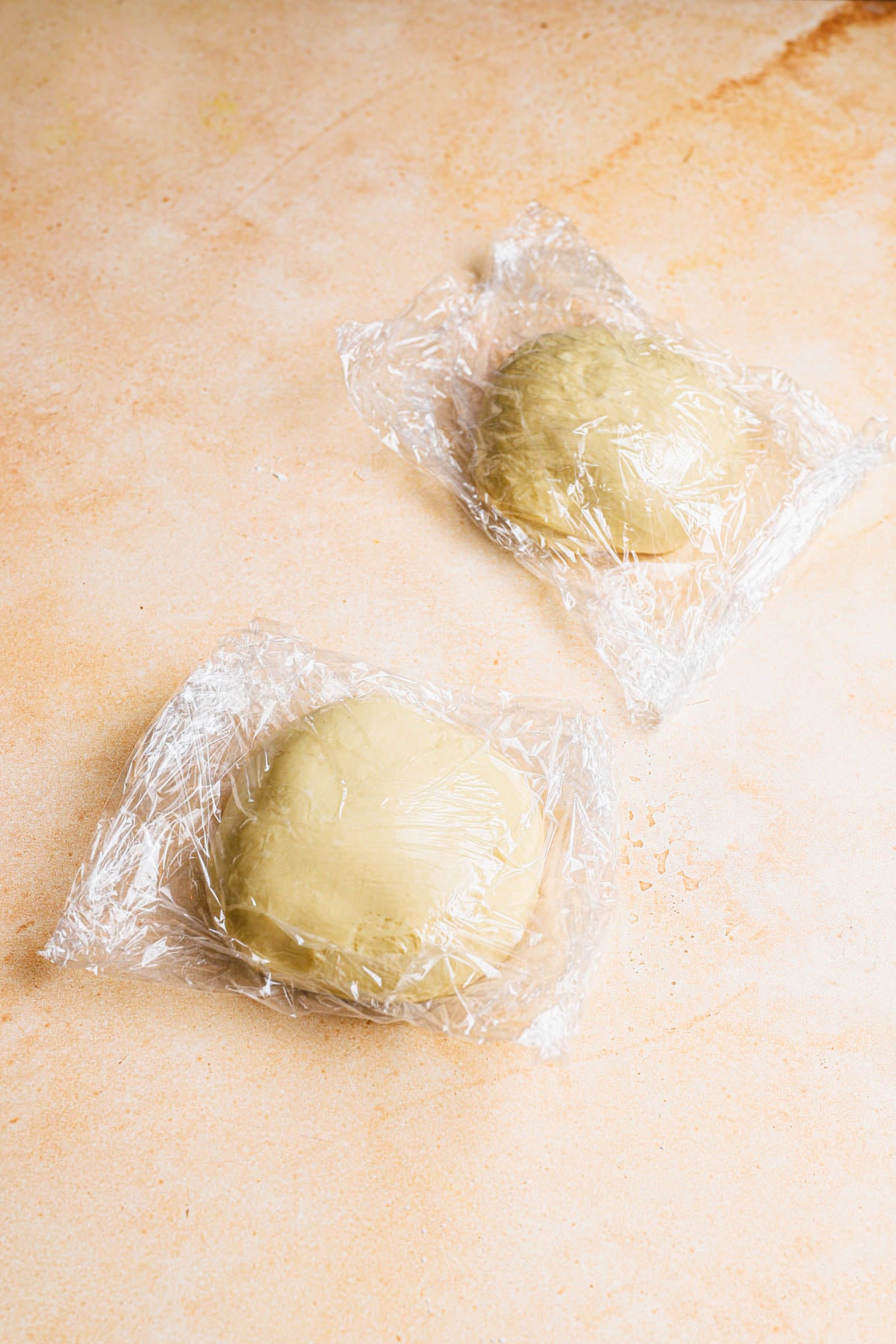 Portuguese brioche dough divide into two, wrapped with plastic wrap.
