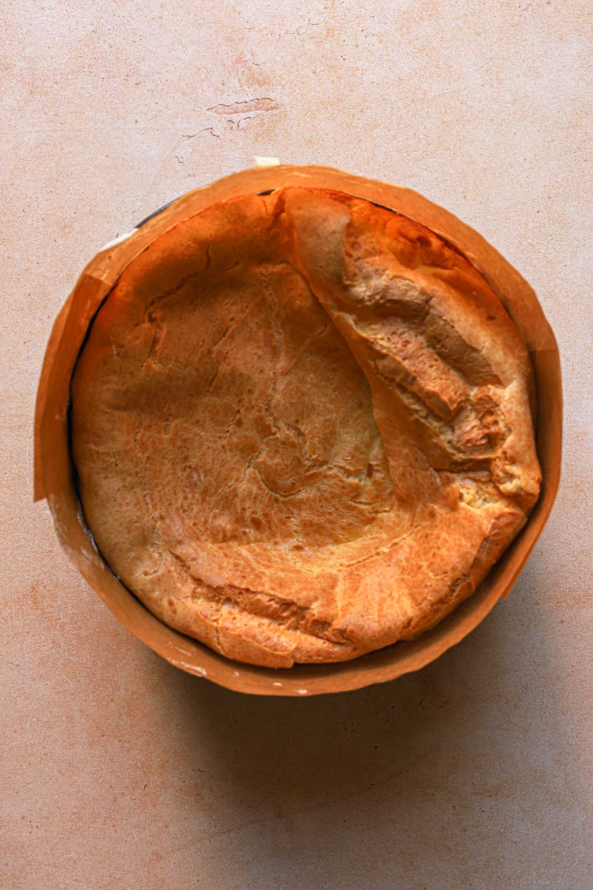 A cream puff cake filled with cream and another layer of cream puff cake. in a pan lined with parchment paper.