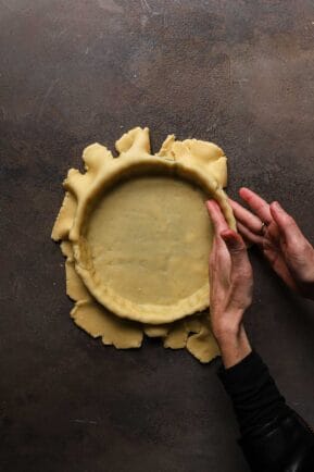 A hand pressing dough into a pan
