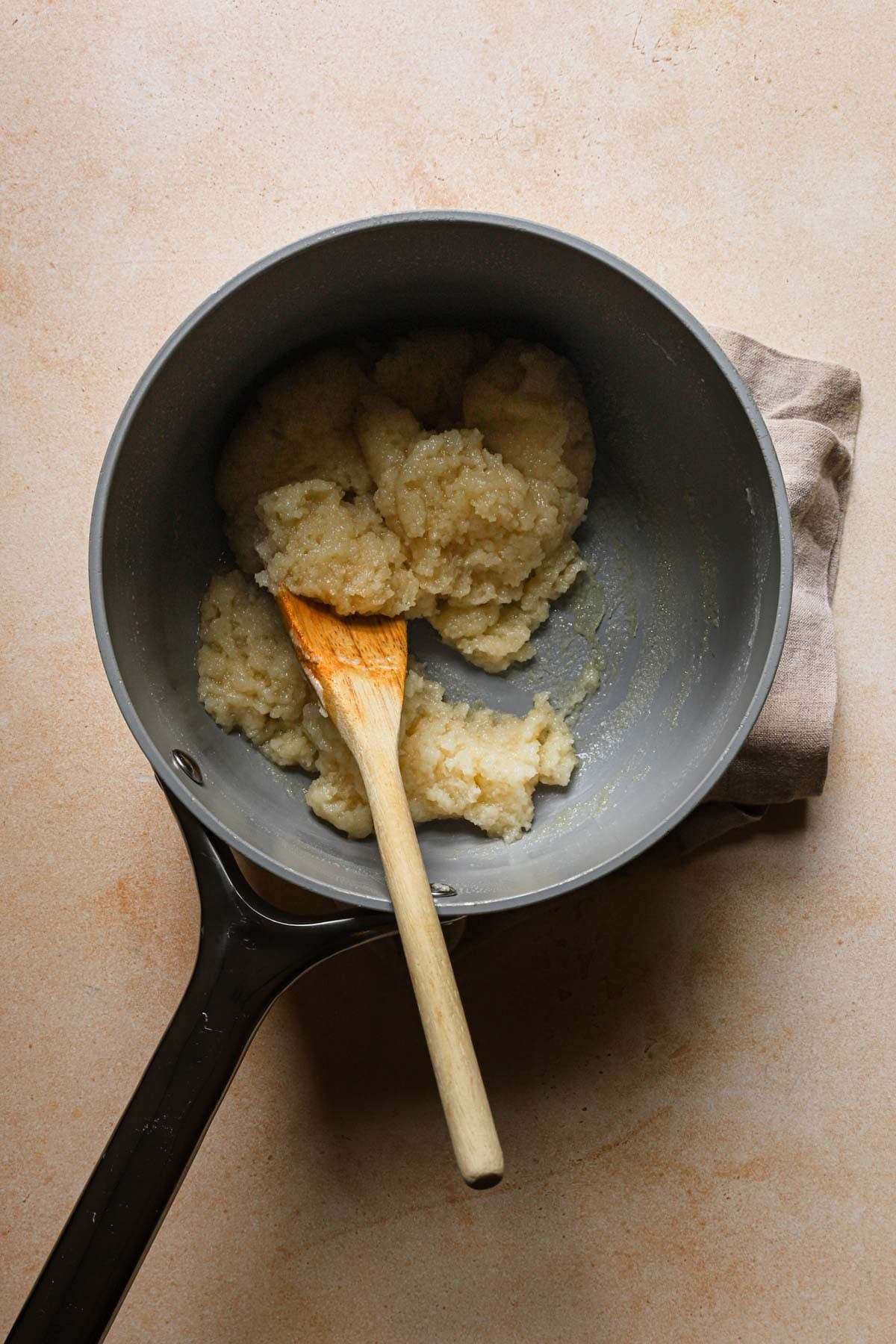 A suace pan with choux paste and a wooden spoon.