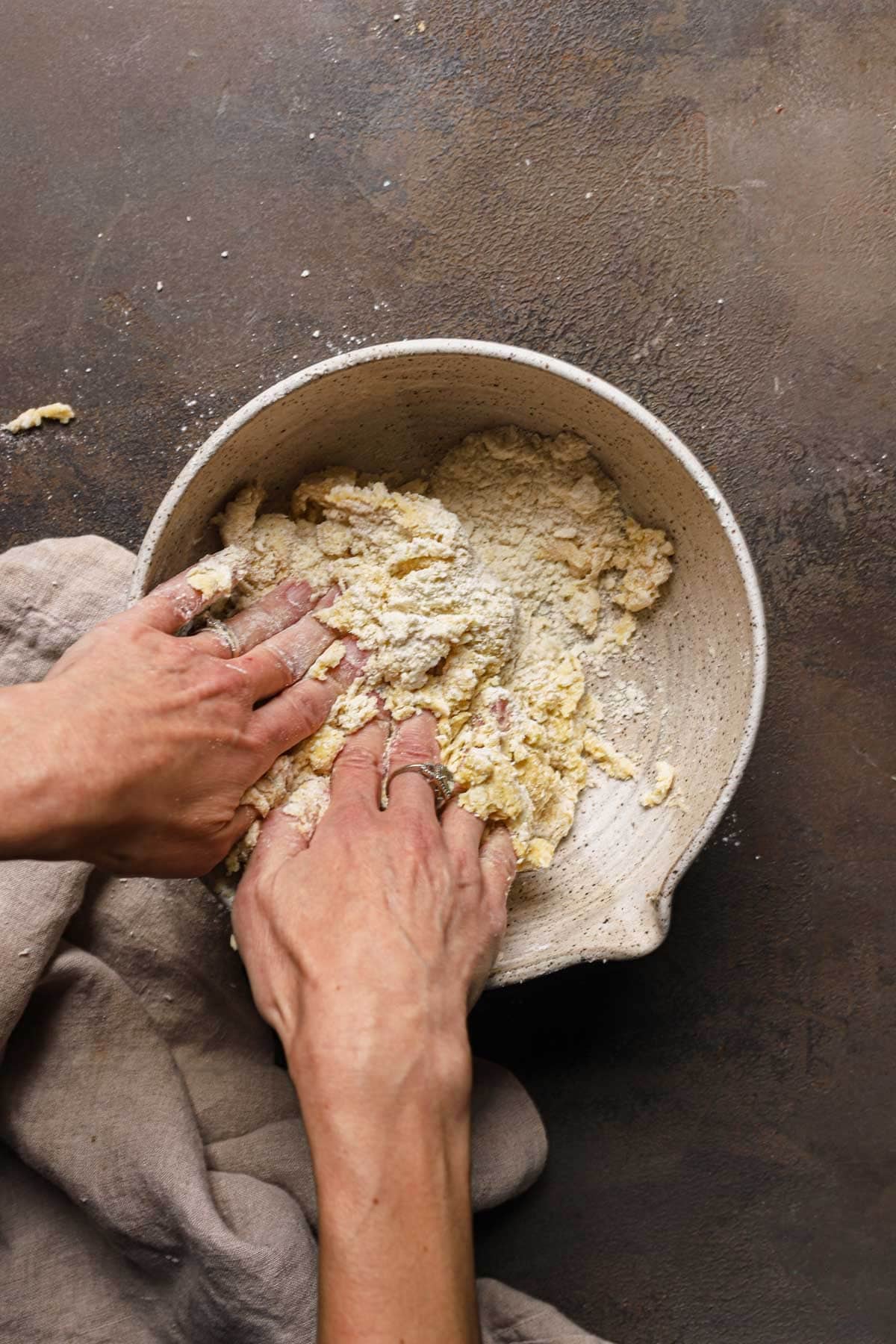 Hand bringing dough together in a large bowl.