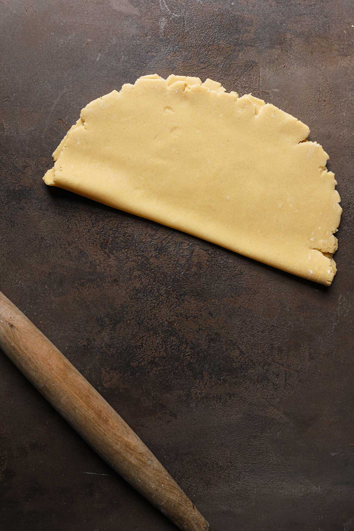 Rolled dough folded over itself next to a rolling pin.