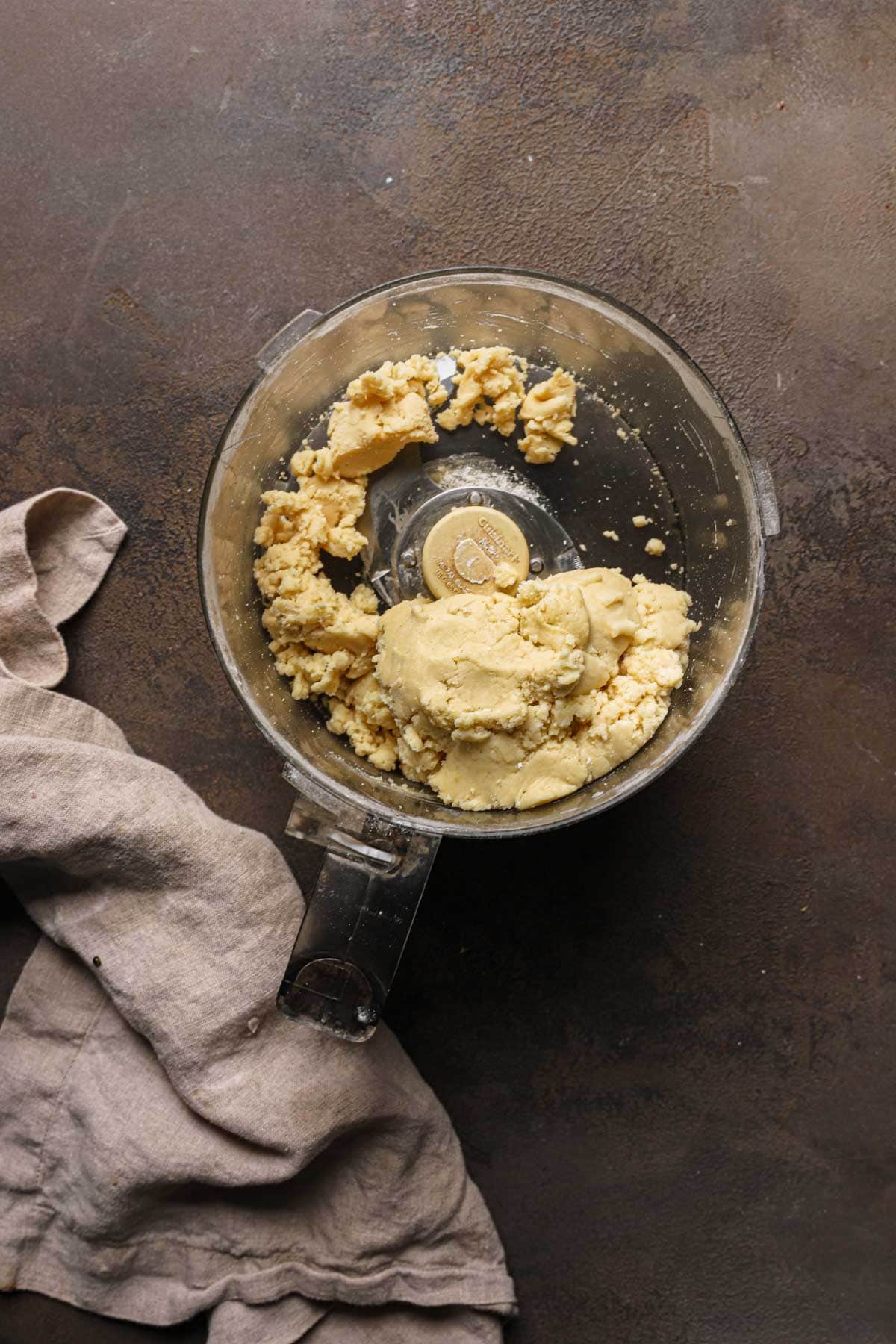 A food processor bowl with pasta frolla dough.