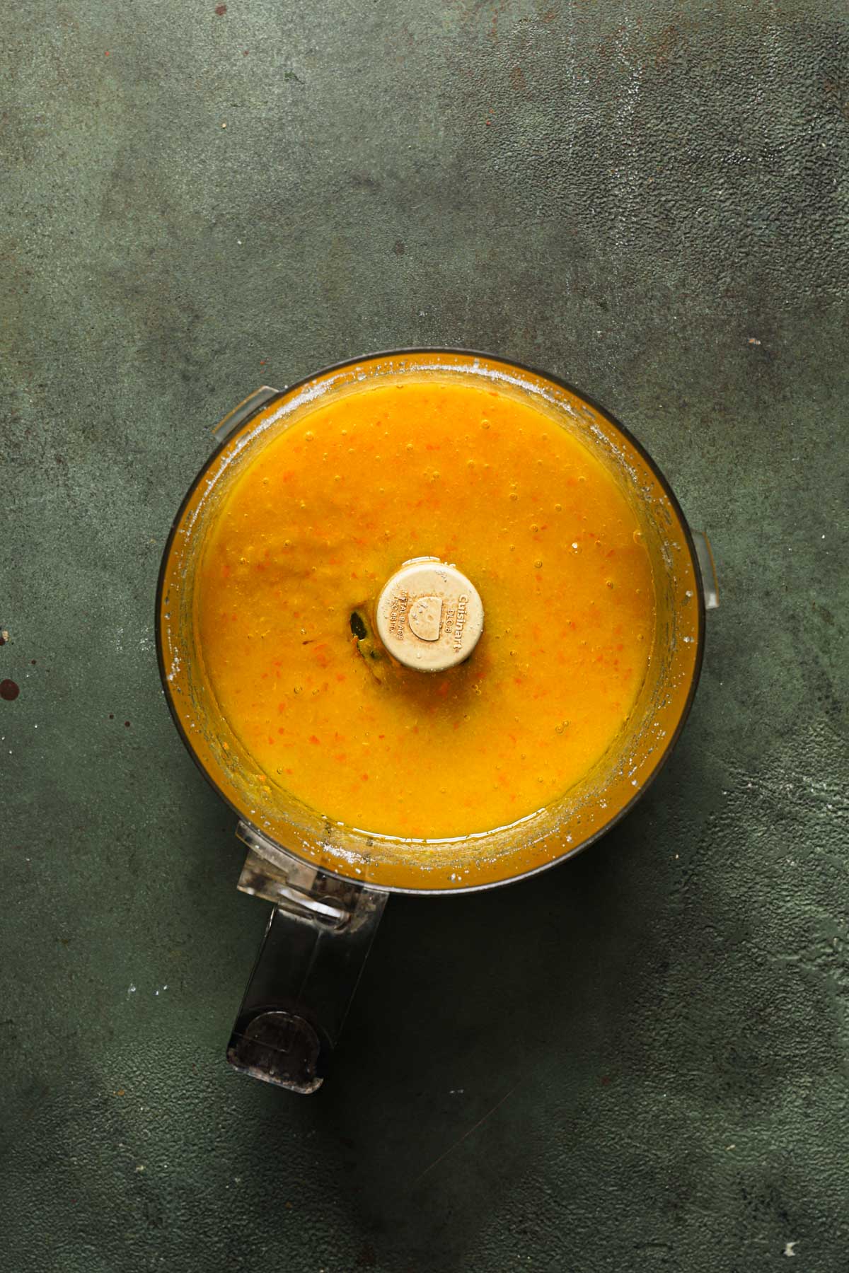 A food processor bowl with pureed fresh orange.