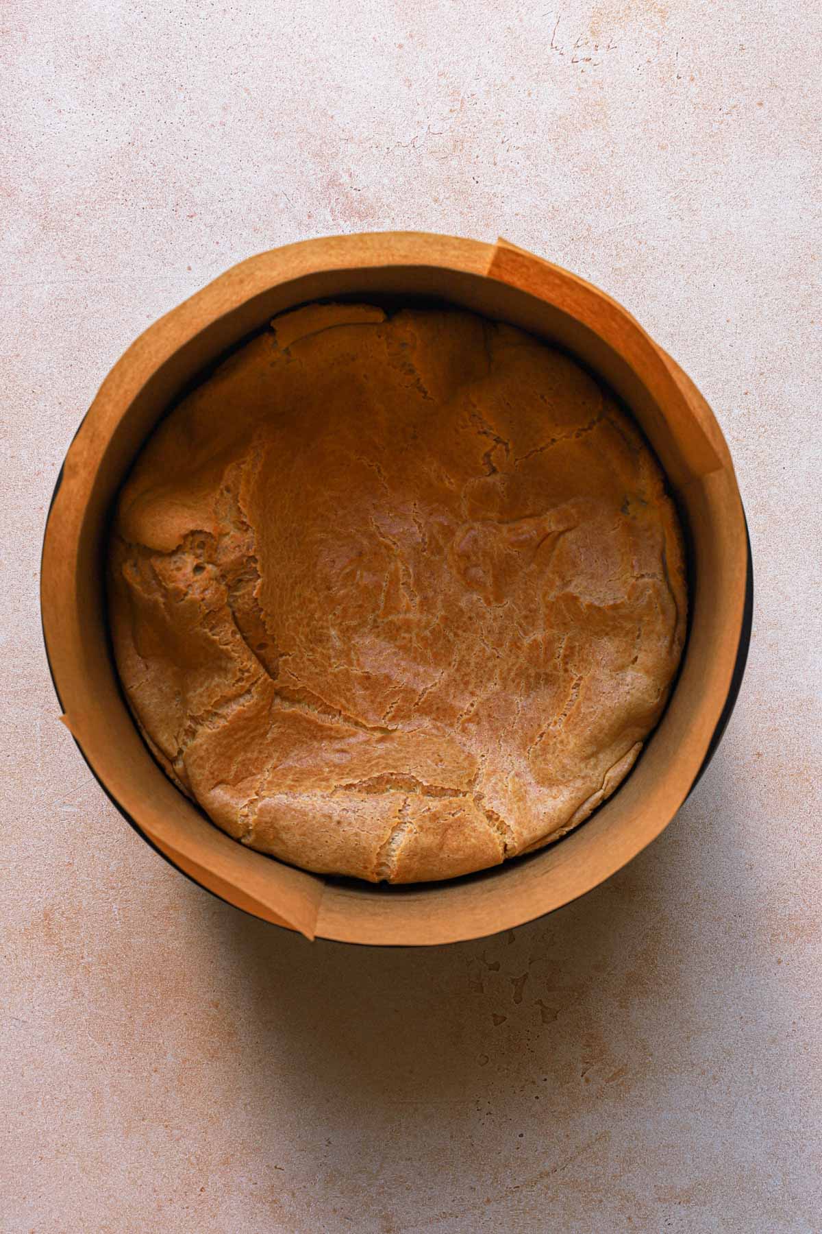 A cream puff cake in a pan lined with parchment paper.