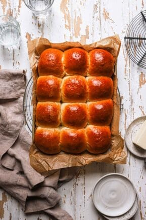 bread rolls in a pan with plates and cups around.