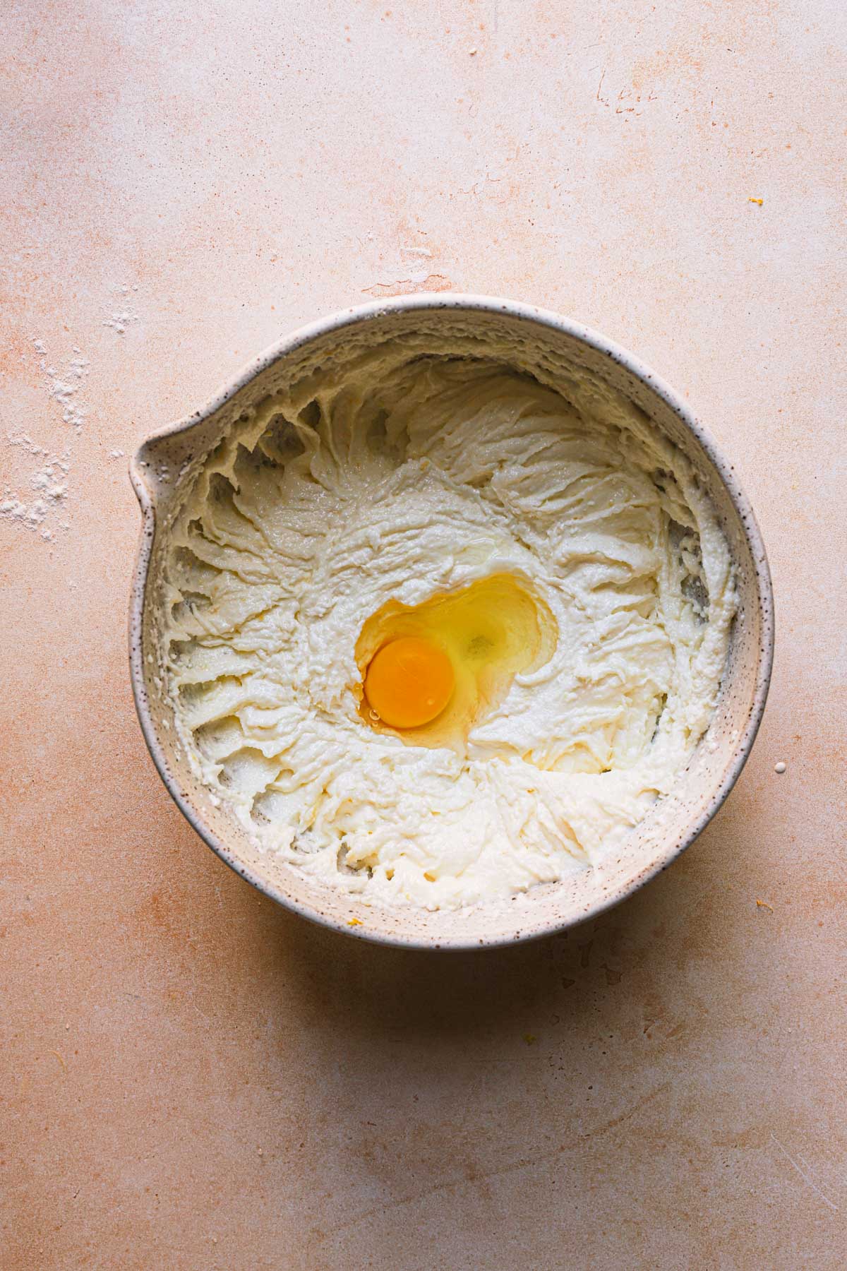 A bowl with creamed butter and sugar and a whole egg.
