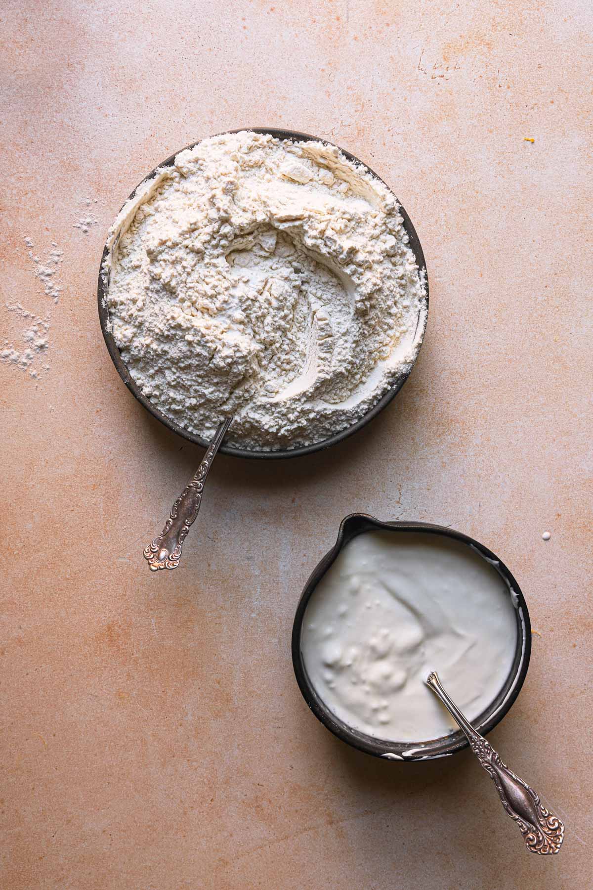 A bowl with flour mixture and a bowl with sour cream.