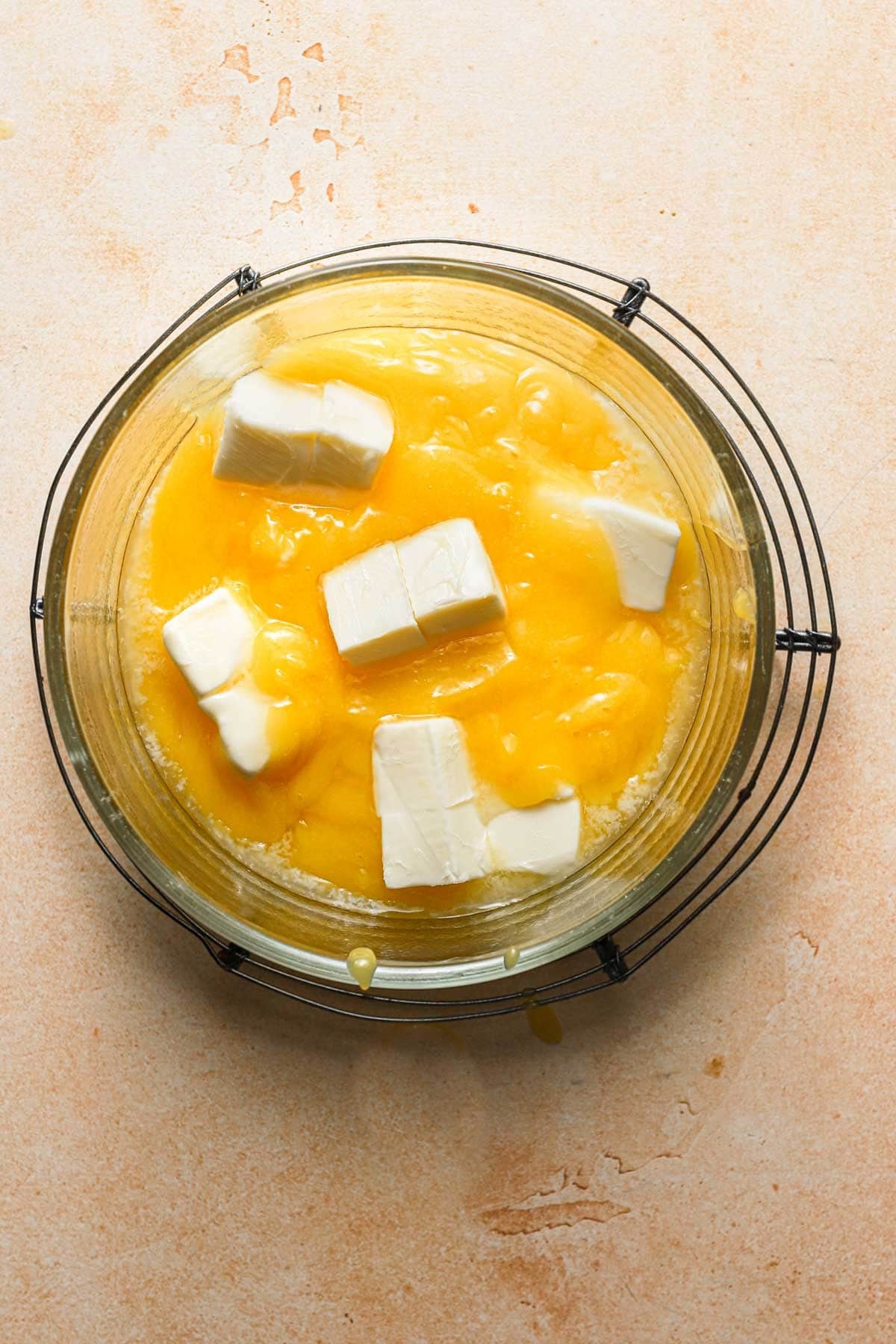 A glass bowl with lemon curd and pieces of butter.