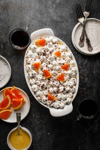 a dish with italian dessert, coffee, plates and forks around it.
