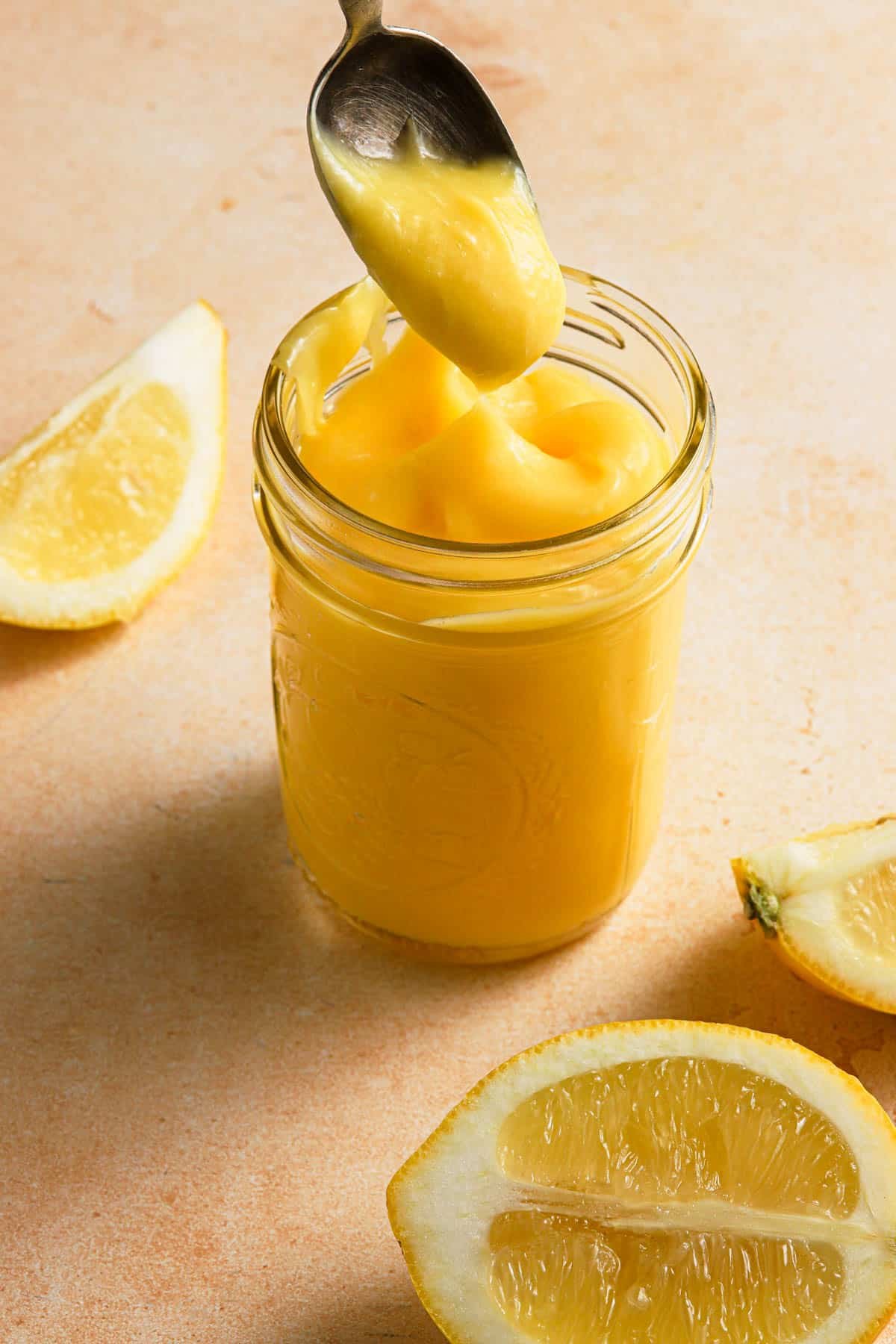 lemon curd in a mason jar with lemons around.