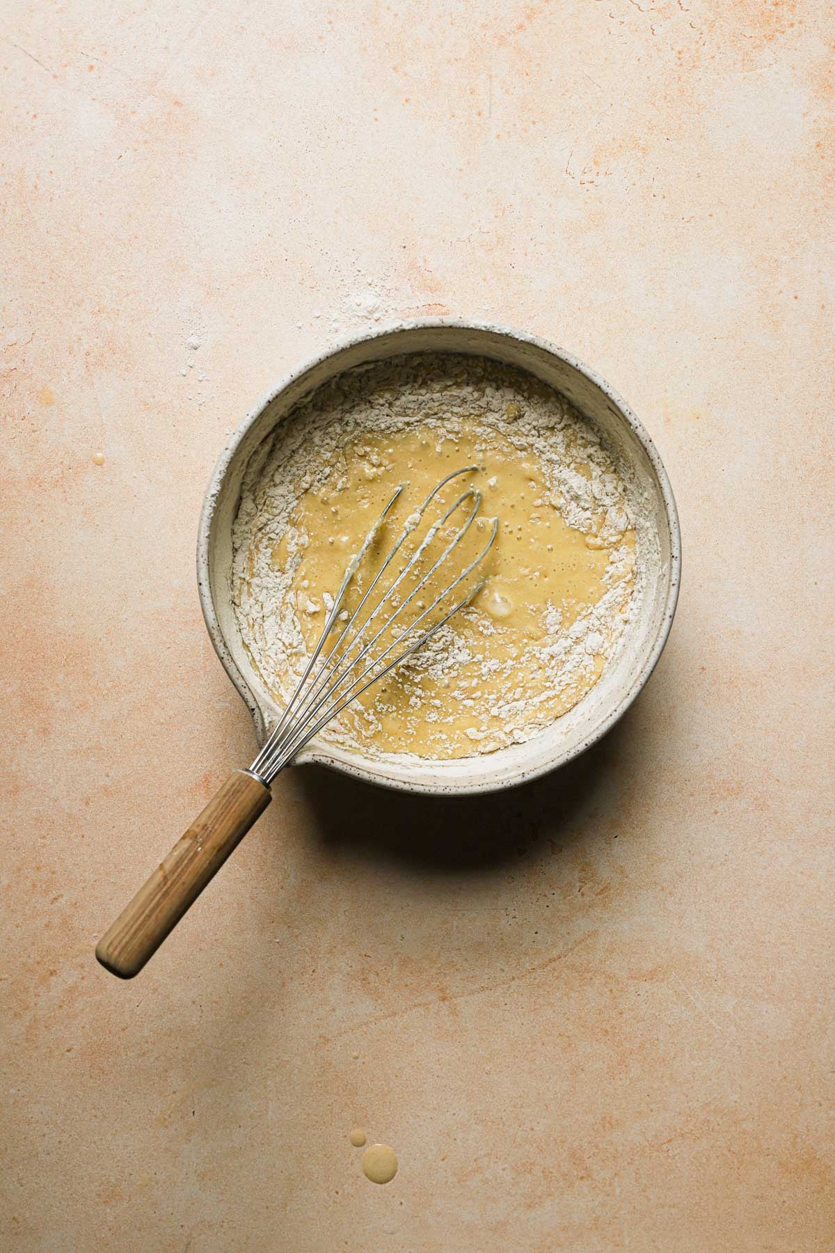 A bowl with a cake batter and a whisk.