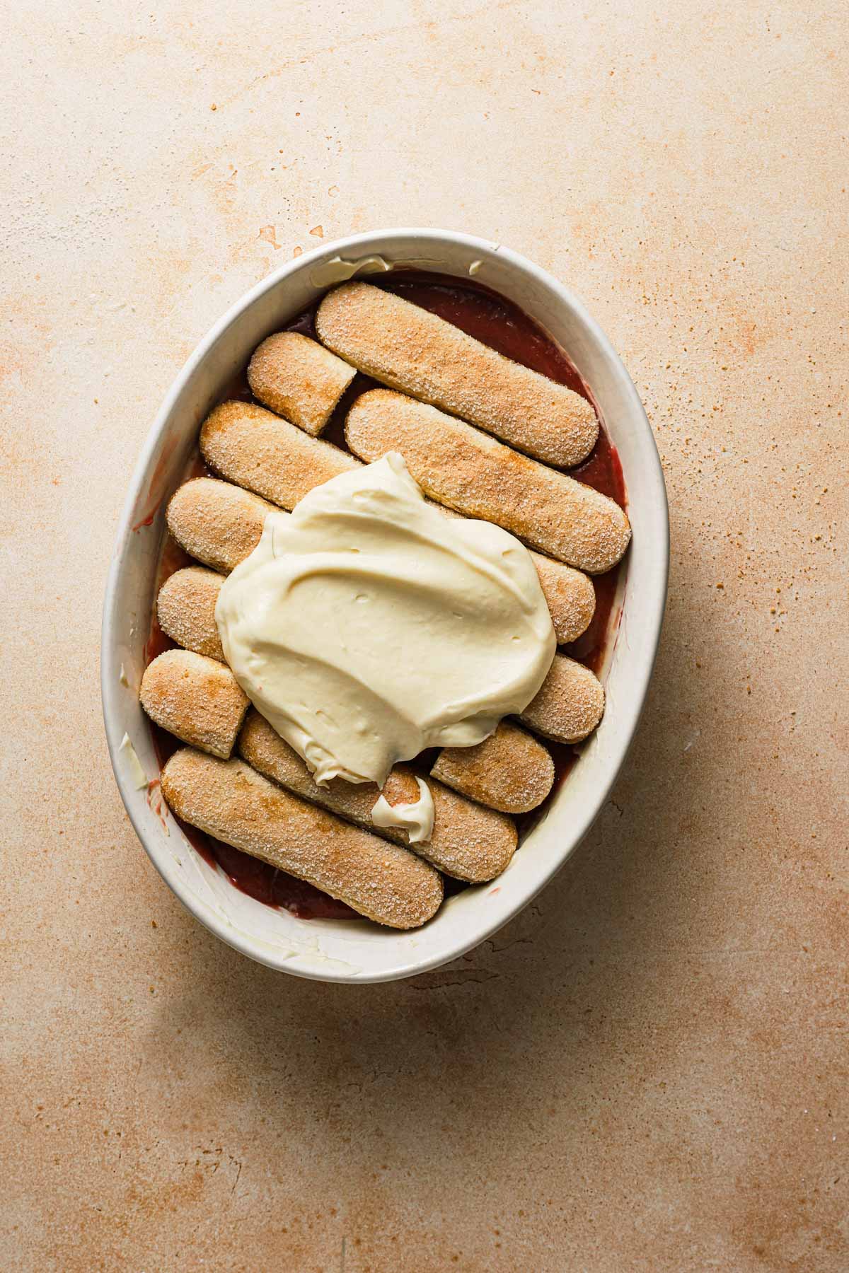 A dish with a layer of ladyfingers a dollop of cream.