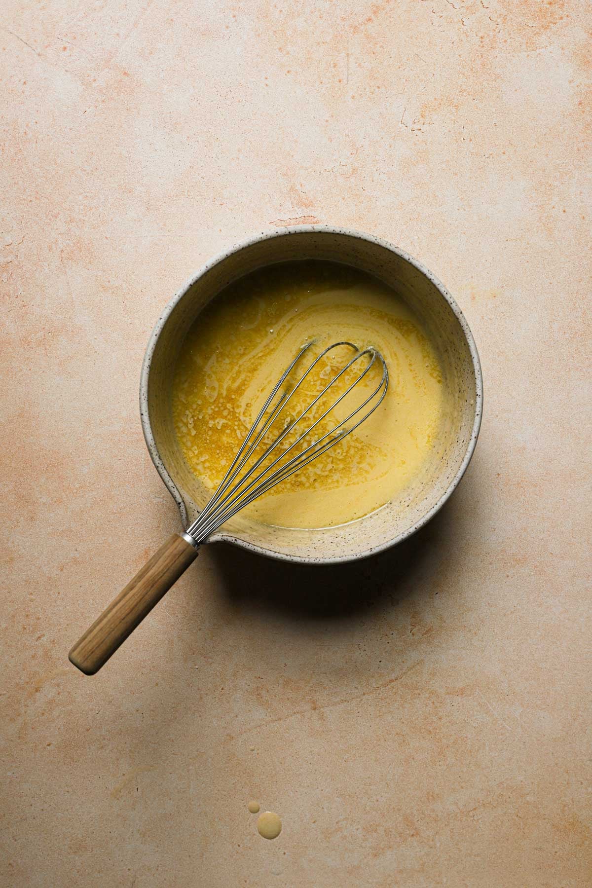A bowl with eggs and sugar mixture, olive oil and a whisk.