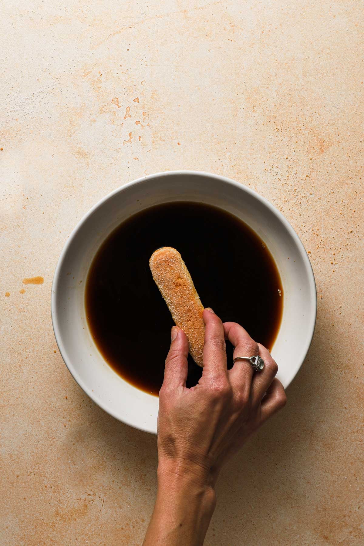 A hand dipping cookie in coffee.