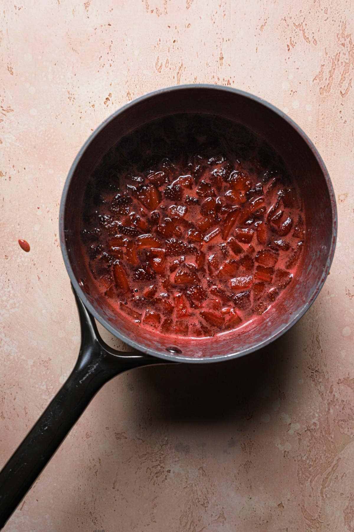 A sauce pan with chopped cookies strawberries in syrup.