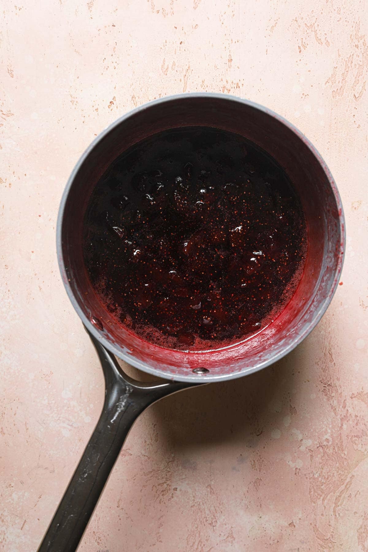 A sauce pan with cookies strawberries preserves.