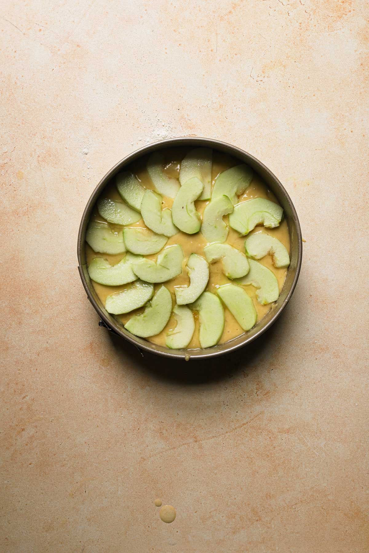 Unbaked italian apple cake topped with sliced apples.