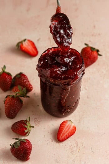 strawberry jam in a jar with a spoon in it.
