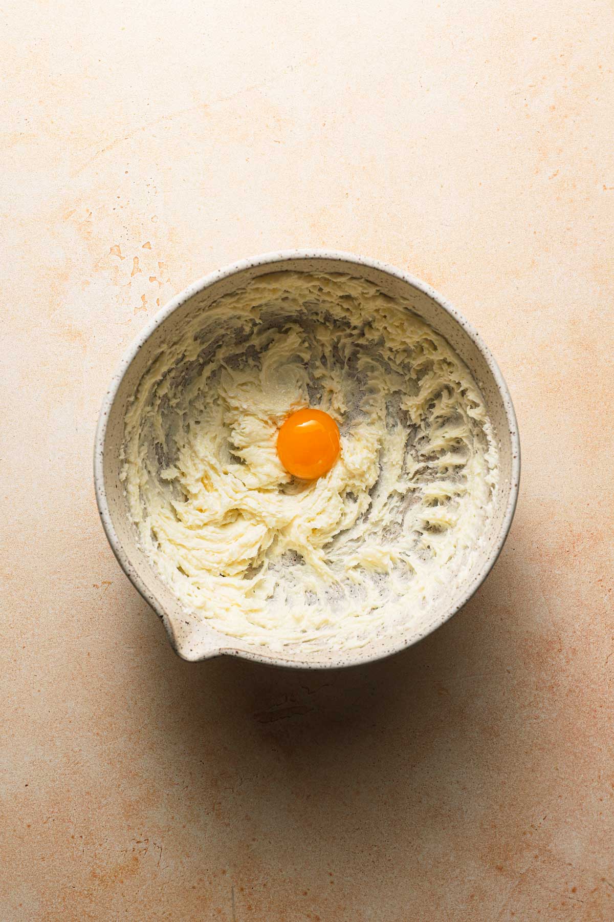 A large bowl with creamed butter and an egg yolk.