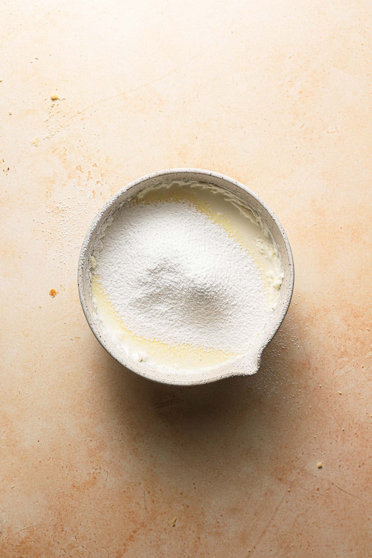 A large bowl with whipped cream and sifted sugar on top.