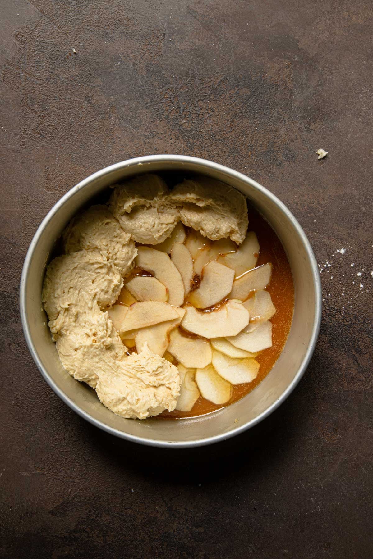 A cake pan with a layer of honey and apples topped with cake batter.
