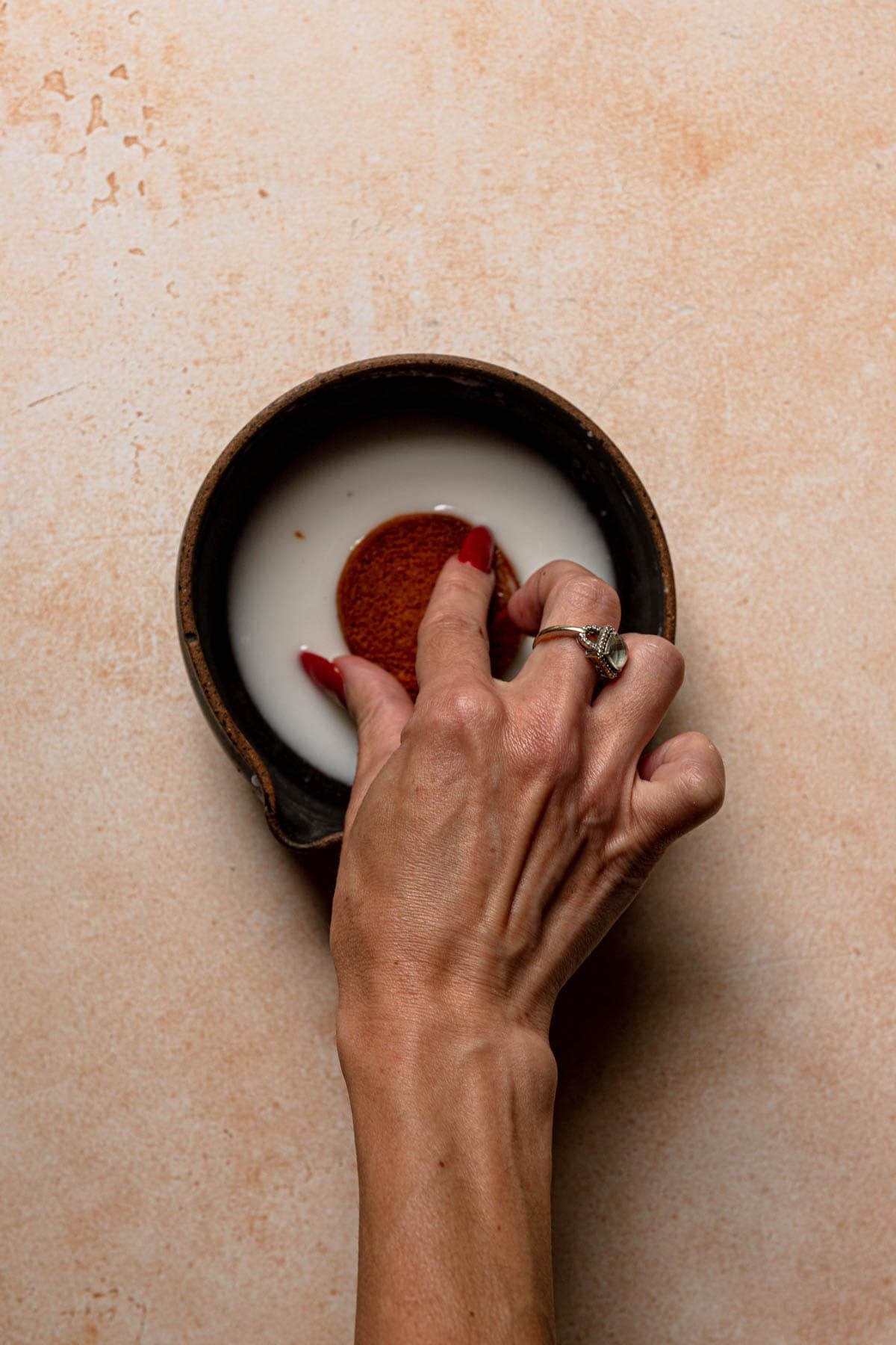 Dipping a cookie into a glaze.