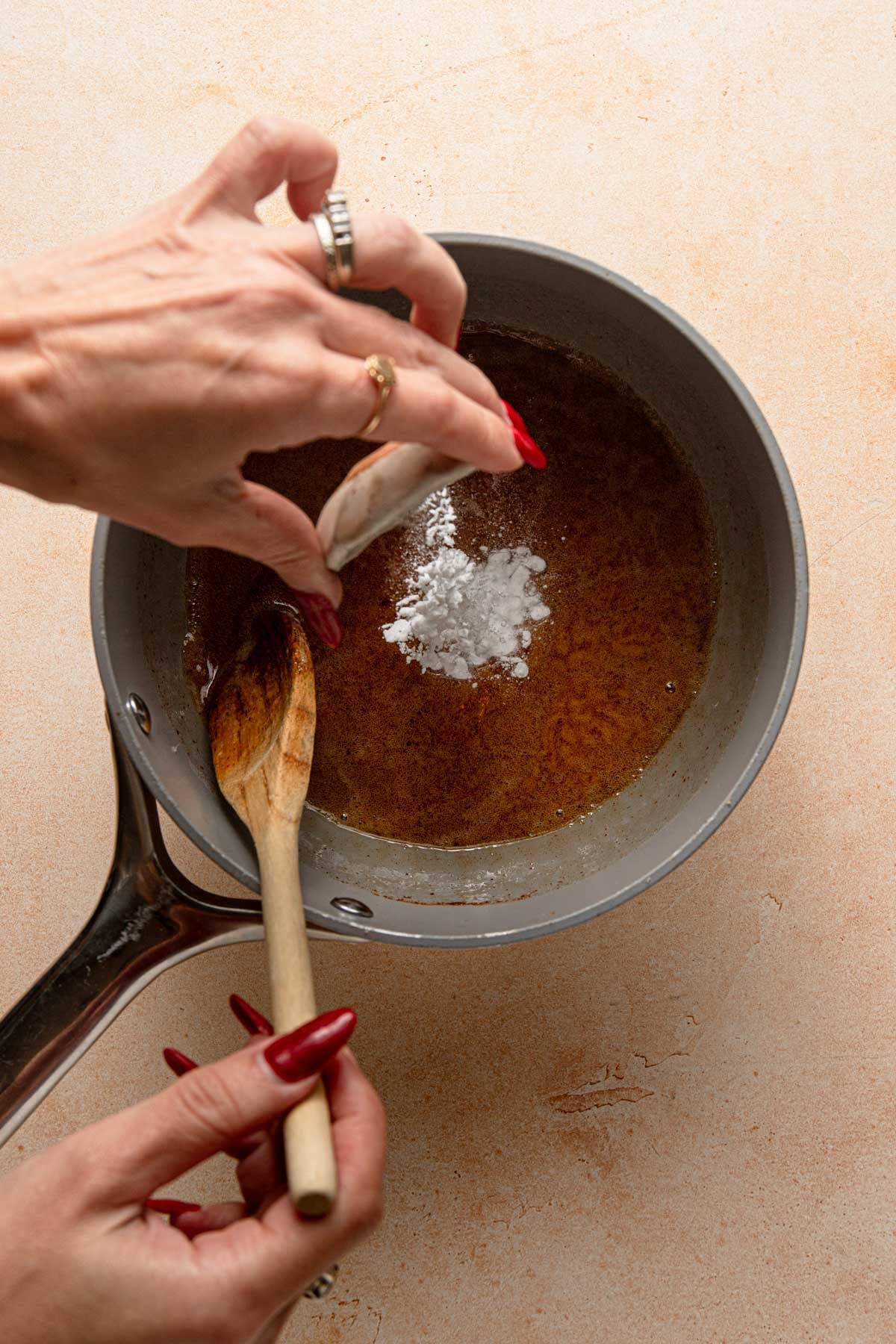 Adding baking soda to honey in a saucepan.