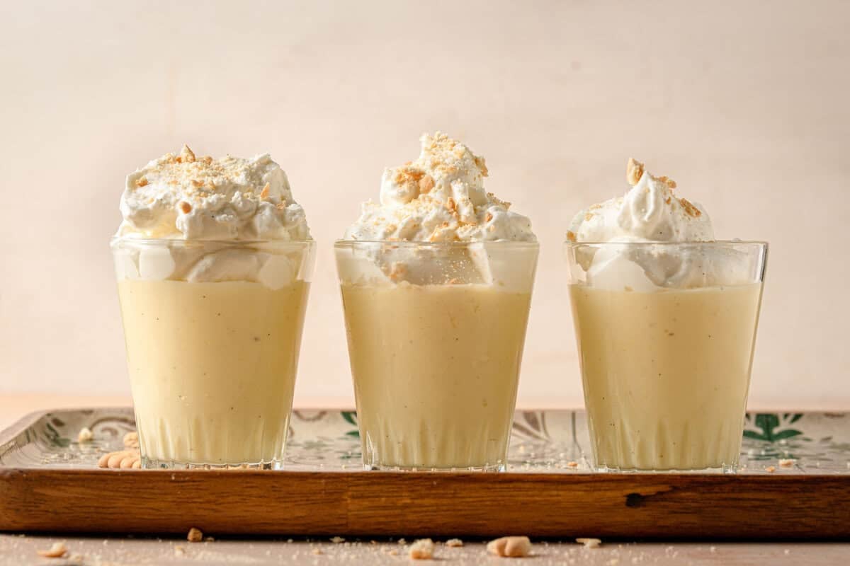 Three dishes filled with Italian pudding topped with cream.