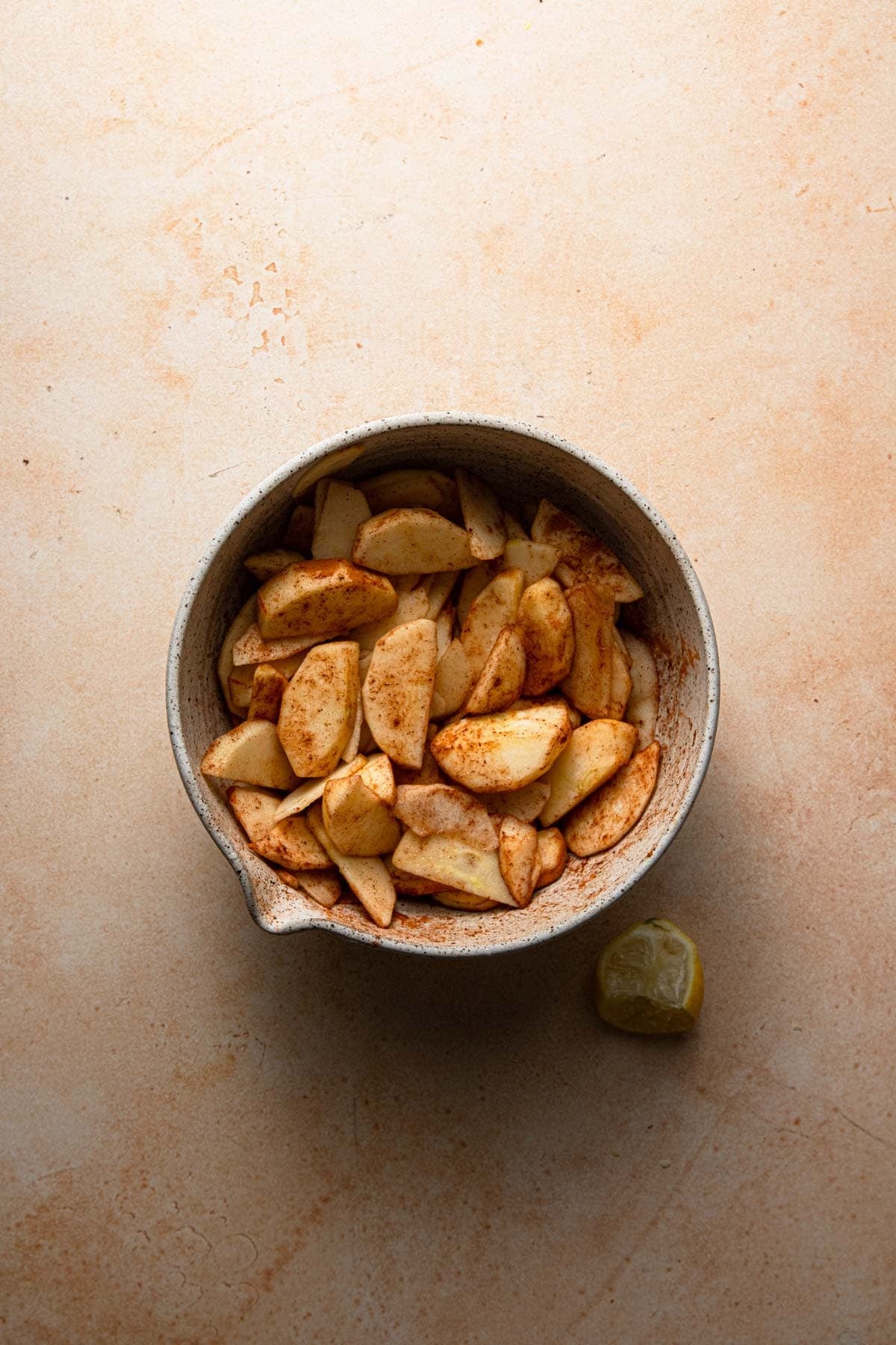 A bowl with sliced apples and cinnamon.